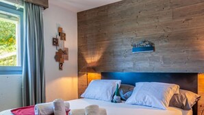 Habitación de hotel con una cama grande, cabecera de madera y vistas a zonas verdes.