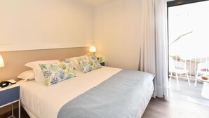 Een hotelkamer met een bed, nachtkastje, lamp en uitzicht.