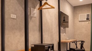 A bunk bed with a wooden frame and a desk with a chair in a room with a light wooden floor and a grey wall. - Primeway Suites Cebu (Cebu City)
