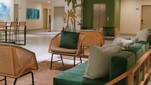 A spacious lobby with a green sofa, wicker chairs, and a large plant. - Primeway Suites Cebu (Cebu City)