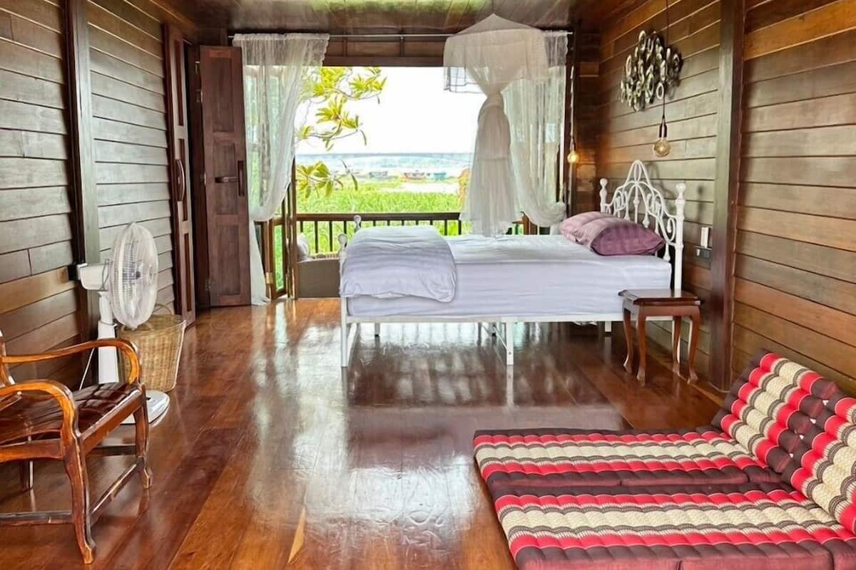 Une pièce en bois avec un lit, une chaise et une vue sur l’océan.