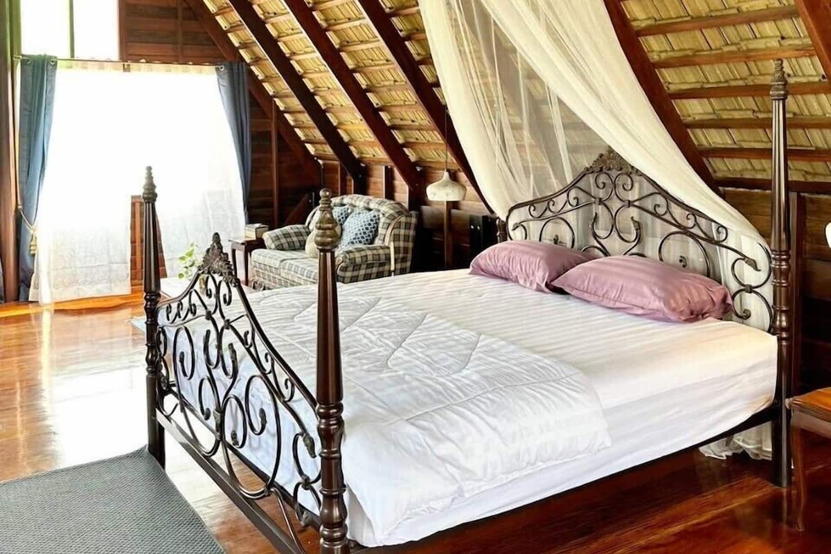 Une chambre avec un plafond en bois, un lit à baldaquin et une moustiquaire.