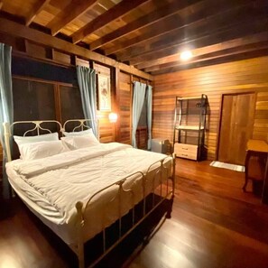 Un dormitorio con paneles de madera, un marco de cama metálico, una mesita de noche y un tocador.