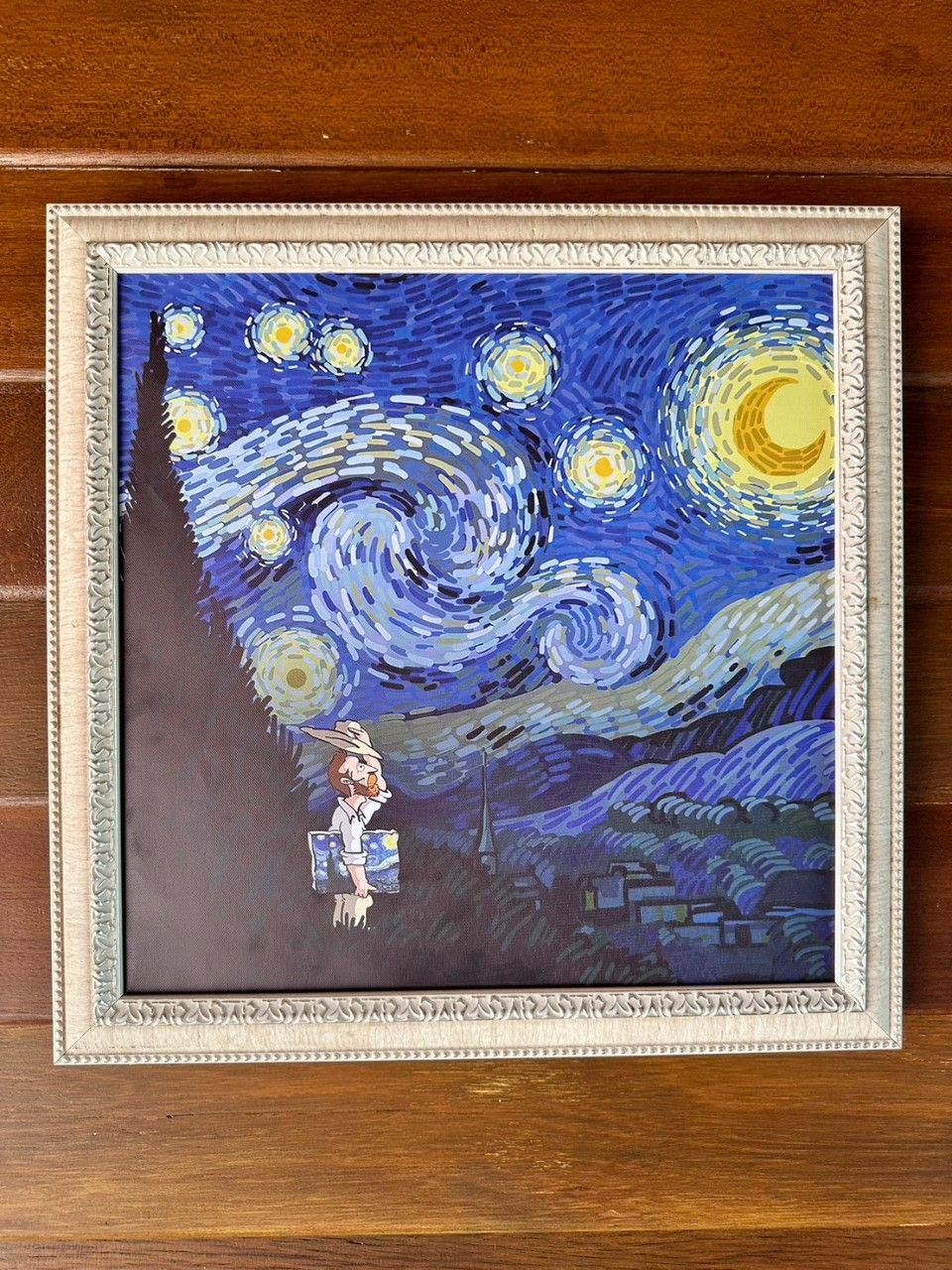 Une œuvre d’art encadrée représentant une nuit étoilée, avec une silhouette se tenant sous le ciel.