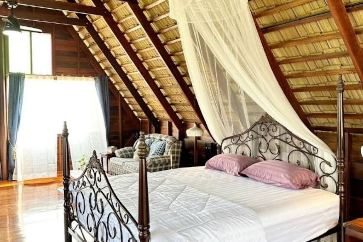A bedroom with a wooden ceiling, a four-poster bed, and a canopy.