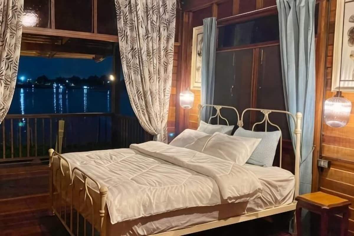Un lit avec une literie blanche, une tête de lit en bois et une table de chevet avec une lampe.