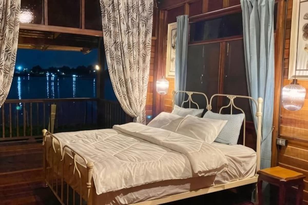 A bed with white bedding, a wooden headboard, and a nightstand with a lamp.