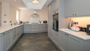 A modern kitchen with grey cabinets, a built-in oven, a microwave, and a coffee machine. - Homeland (Somerton)