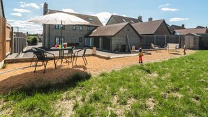 A residential area with a house featuring a patio with outdoor furniture and a large umbrella. - Homeland (Somerton)