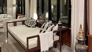 Una habitación amplia con una cama grande, una mesita de noche con lámpara y un jarrón decorativo.