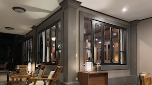 Un comedor con mobiliario de madera y ventanas amplias.