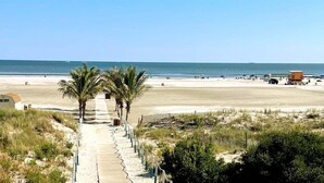 A beach pathway leading to the ocean with palm trees, a lifeguard tower, and a sandy beach. - Residence 101 at The Grand (Wildwood)
