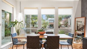 Un comedor con una mesa grande, cuatro sillas y una planta en maceta.
