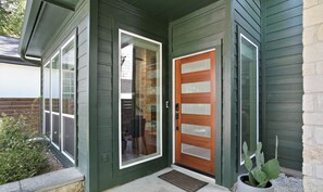 A house with a green exterior, a wooden front door, and a potted plant. - Stylish Retreat + Outdoor Oasis in Heart of Austin (Austin)
