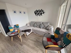 Un soggiorno moderno con un divano, due poltrone a fantasia, un tavolino e un elemento decorativo a parete.