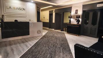A hotel lobby with a reception desk, a carpeted area, and a seating area with a black sofa.