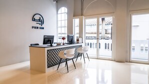 A modern reception desk with a logo, two computer monitors, and a red lamp. There are two white chairs in front of the desk. - PIER 808 Hostel (Bangkok)