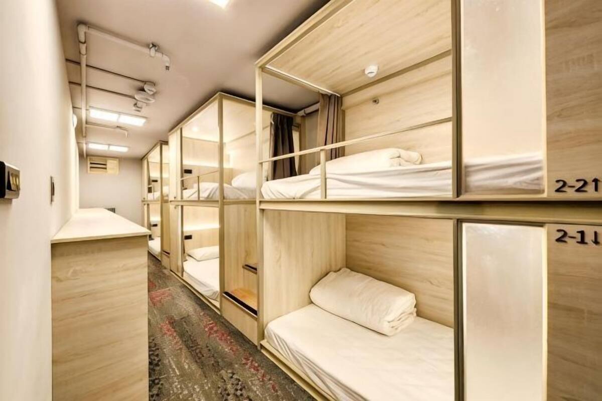 A corridor with bunk beds, each labeled with room numbers, and a wooden floor.
