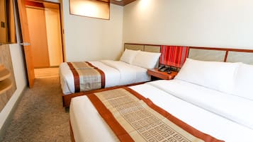 Habitación de hotel con dos camas, cabecera de madera, mesita de noche con teléfono y suelo alfombrado.