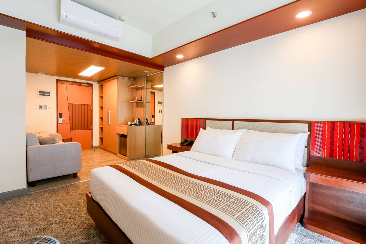 Una habitación de hotel con una cama grande, un sofá, un escritorio y un espejo.