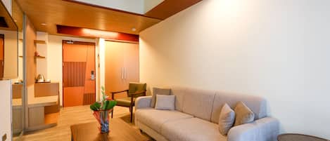 Una sala moderna con un sofá, una mesita de centro y una pequeña mesita auxiliar. Tiene un techo de madera y una puerta que da a otra habitación.