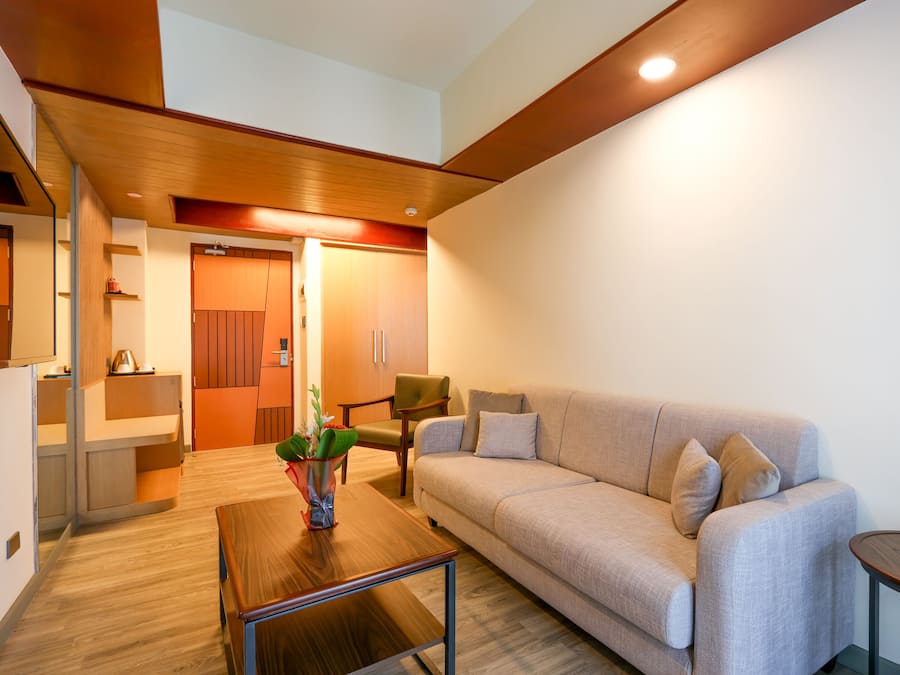Een moderne woonkamer met een bank, een salontafel en een klein bijzettafeltje. Er is een houten plafond en een deur die naar een andere kamer leidt.