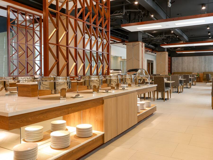 Ein modernes Restaurant mit einer langen Theke, Holzabtrennungen und ordentlich gestapelten Tellern.