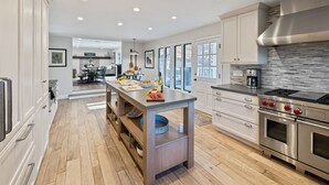 A modern kitchen with a central island, stainless steel appliances, and a view to the dining area.