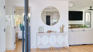 A modern living room with a white console table, a large round mirror, and a beige sofa. - Element by AvantStay | Pool, Firepit, Game Room (Scottsdale)