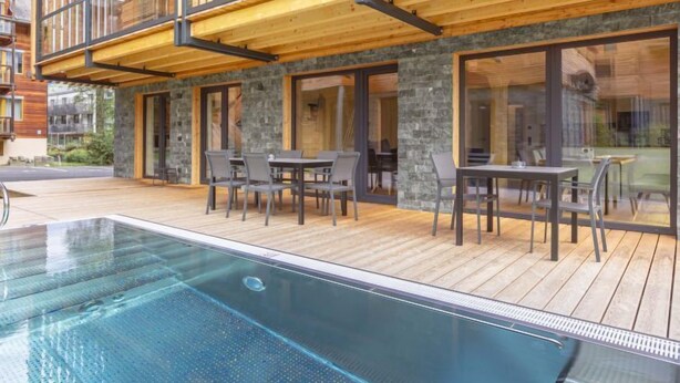 Un bâtiment moderne doté d’une piscine, d’un espace extérieur aménagé et d’une façade en pierre.
