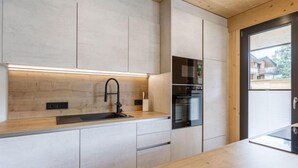 Une cuisine moderne avec un plan de travail en bois, un robinet noir et des appareils électroménagers intégrés.
