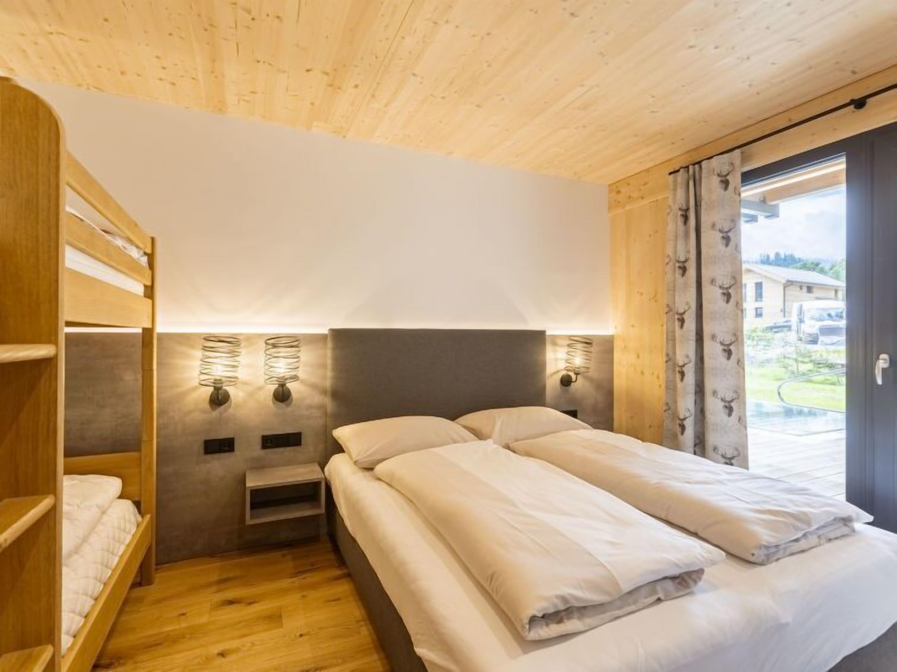 Ein Schlafzimmer mit einem Etagenbett, einem Einzelbett, Holzboden und Blick nach außen.