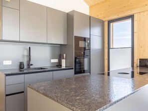 Une cuisine moderne avec des meubles de couleur grise, un plan de travail en granit et des appareils électroménagers intégrés.
