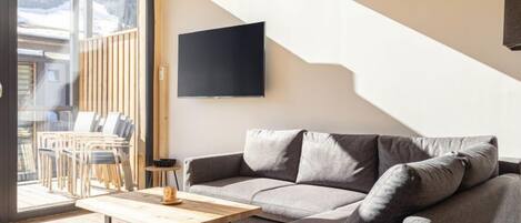 A modern living room with a sofa, a coffee table, and a TV mounted on the wall.
