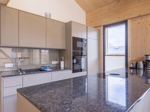 Una cocina moderna con encimera de granito, electrodomésticos de acero inoxidable y un amplio ventanal que proporciona luz natural.