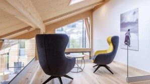 Un intérieur moderne avec un plafond haut et une verrière, comprenant deux fauteuils et une petite table.