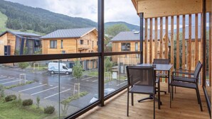 A modern wooden cabin with a balcony, large windows, and a view of a parking area and other cabins. - Penthouse # 4b mit Sauna&Außenbadewanne by Interhome (Sankt Georgen am Kreischberg)