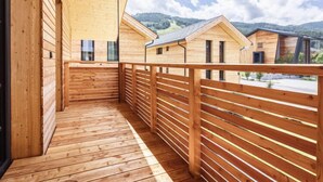 A wooden balcony with a view of multiple cabins in a mountainous area. - #6b mit Sauna & Pool by Interhome (Sankt Georgen am Kreischberg)