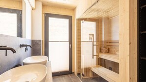 Un baño moderno con dos lavamanos, cabina de ducha con mampara de vidrio y muebles de madera.
