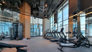 Une salle de sport équipée de tapis de course, d’appareils de musculation et d’un banc.