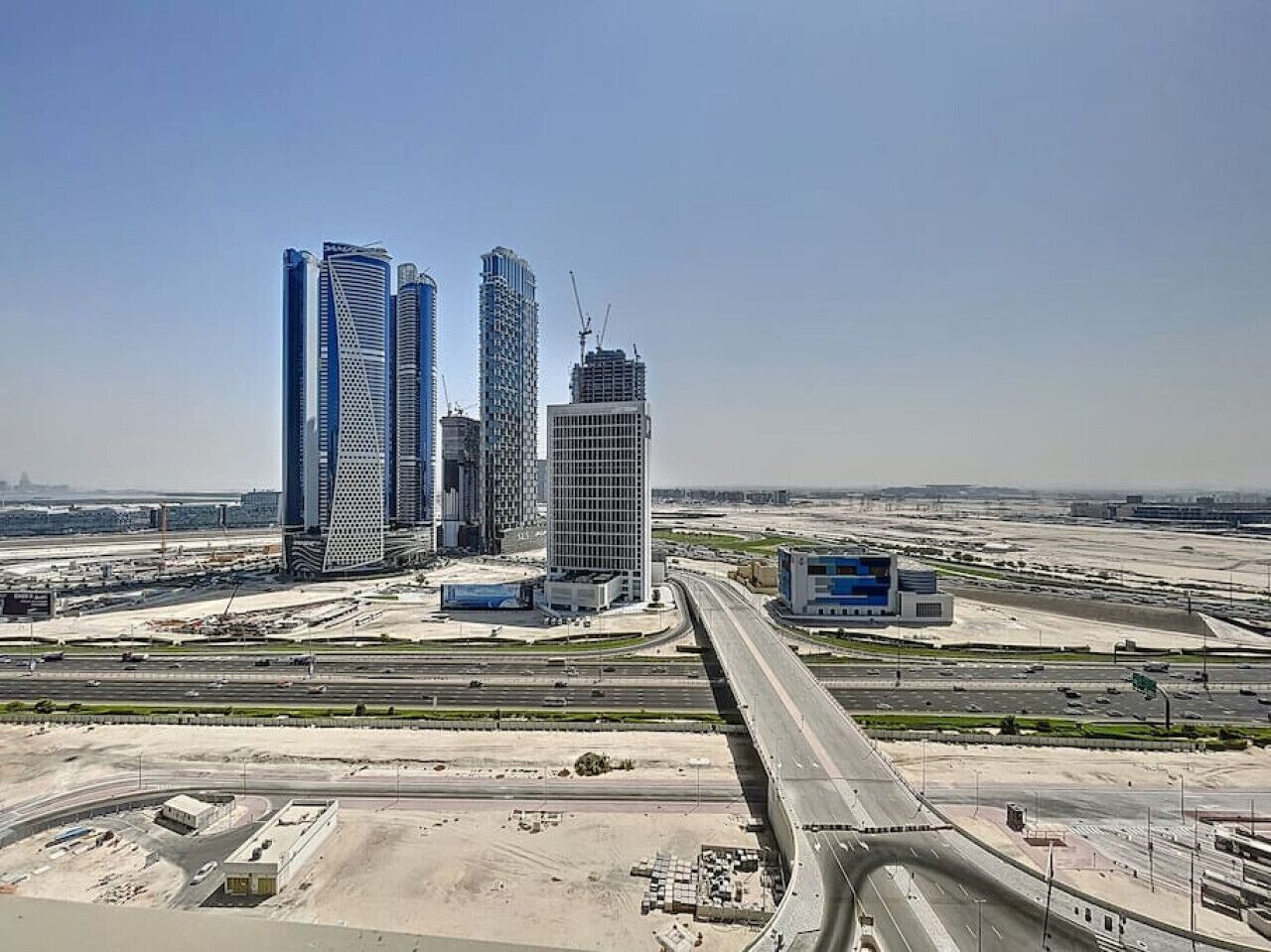 Een hoog gebouwde complex met meerdere wolkenkrabbers, een snelweg en bouwplaatsen.