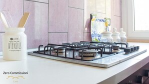 A kitchen with a gas stove, a jar of utensils, and a window with blinds. - Palm Beach House - Sea and Beach View (Montesilvano)
