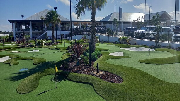 Un campo de golf con un moderno club de campo al fondo.