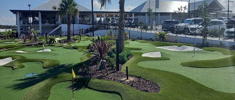 Un campo de golf con un moderno club de campo al fondo.