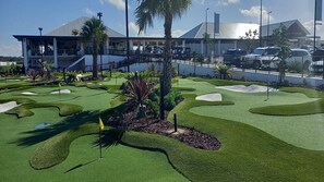 A golf course with a modern clubhouse in the background.