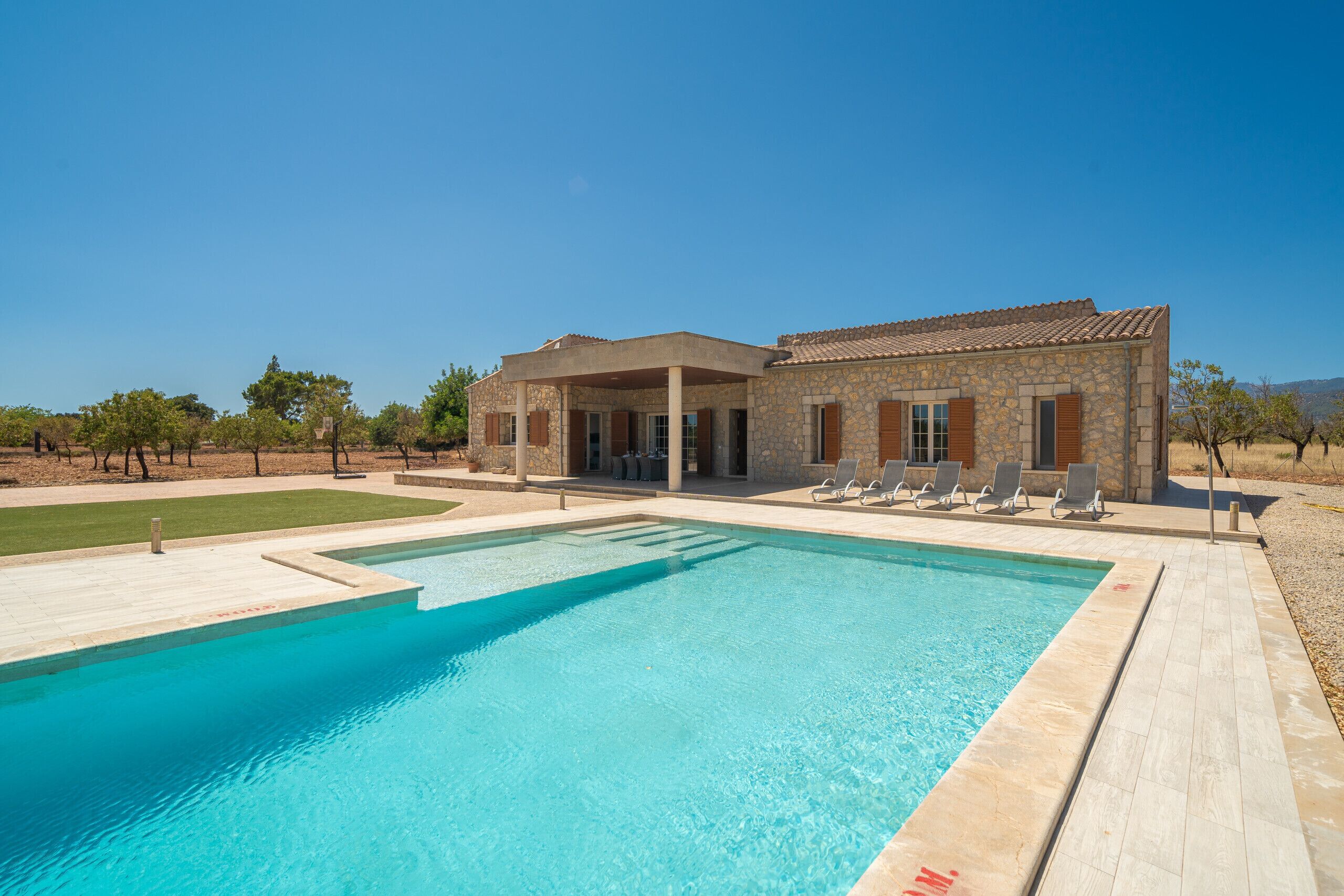 Une maison en pierre avec une piscine et un espace extérieur aménagé pour se détendre.
