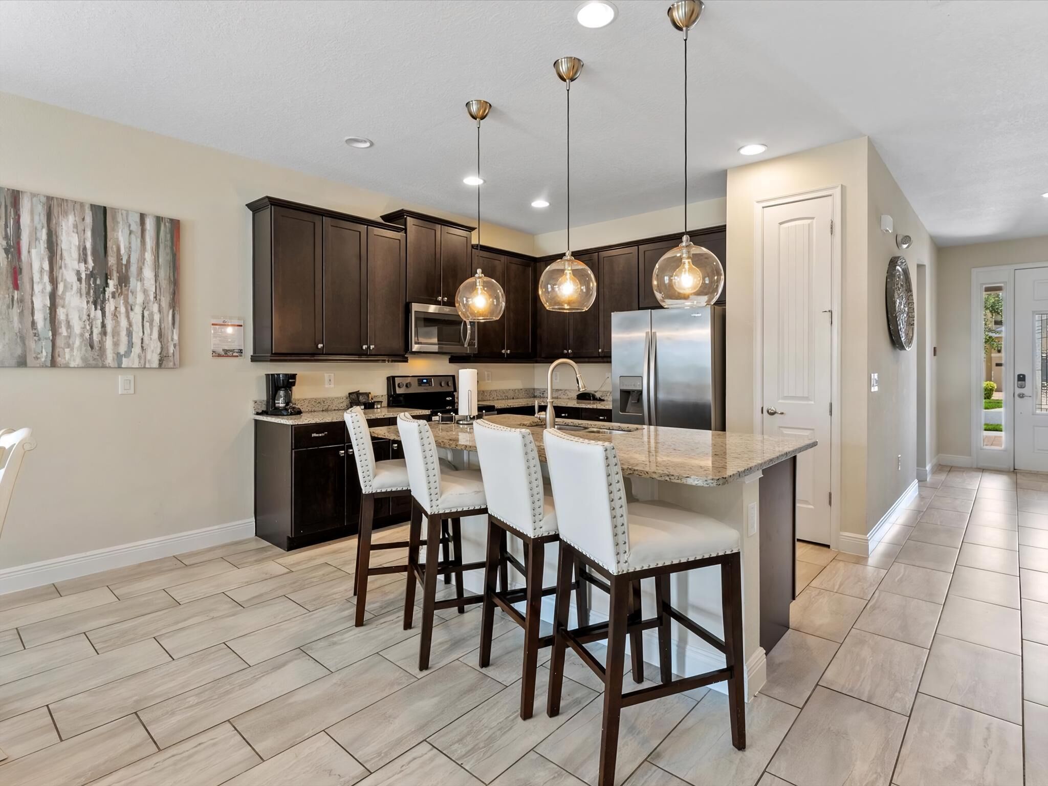 A modern kitchen with dark wood cabinets, stainless steel appliances, and pendant lighting.