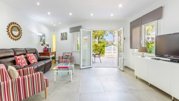Una sala de estar moderna con un sofá, un sillón, una mesa de centro y un televisor sobre un mueble.