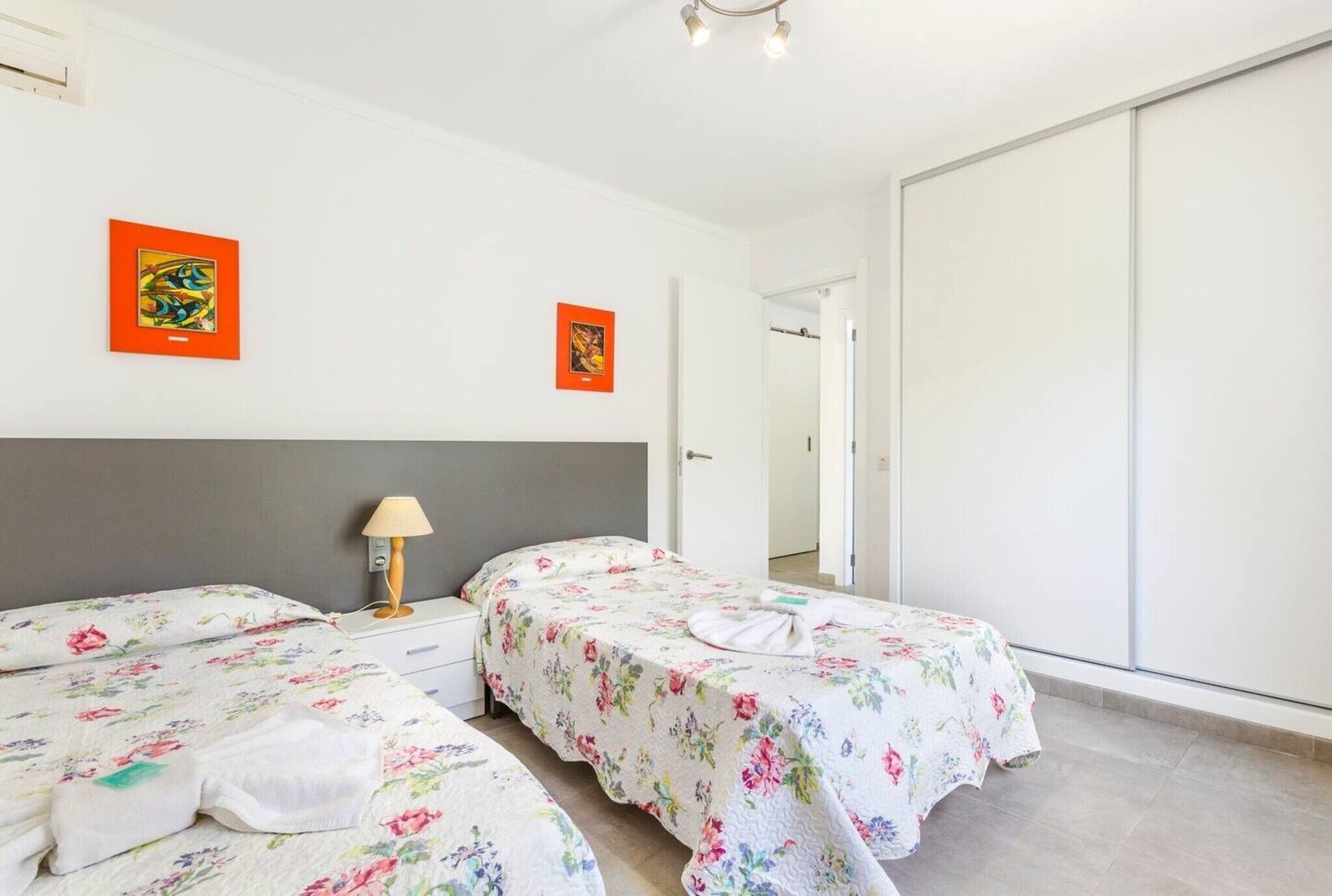 Une chambre d’hôtel avec deux lits, une table de chevet avec une lampe et un grand miroir.