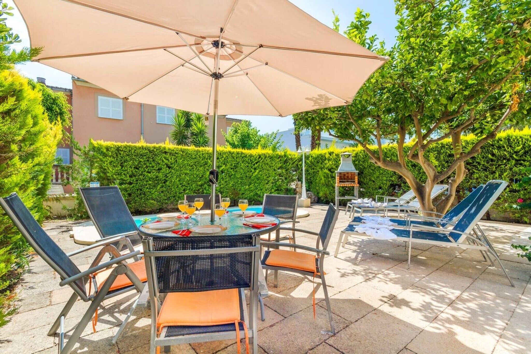 Een terras met een tafel, stoelen en een parasol.